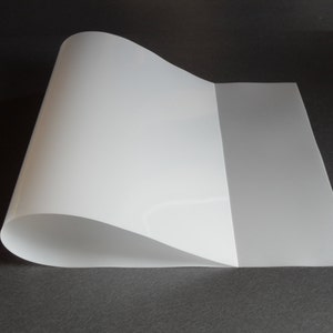May include: A white, translucent sheet of plastic, folded in half, with a slight curve in the middle.
