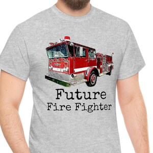 Op de afbeelding: Een grijs T-shirt met een rode brandweerwagen afbeelding en de tekst "Future Fire Fighter".