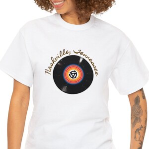 May include: White t-shirt featuring a black vinyl record graphic and the text "Nashville, Tennessee" in gold script.