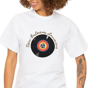 May include: White t-shirt featuring a black vinyl record graphic and the text "New Orleans Louisiana" in gold script.