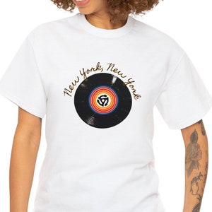 May include: White t-shirt featuring a black vinyl record graphic and the text "New York, New York" in gold script.