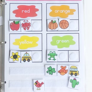 May include: A color sorting activity for kids featuring images of a red apple, crab, pumpkin, basketball, yellow sunflower, taxi, green frog, clover, fish, school bus, and a red cardinal. The activity includes the words "color sort", "red", "orange", "yellow", "green", and white velcro dots.