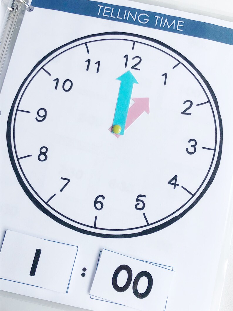 May include: A black and white clock face with the numbers 1 through 12. The hour hand is pointing at the 12 and the minute hand is pointing at the 12. The time is 1:00.