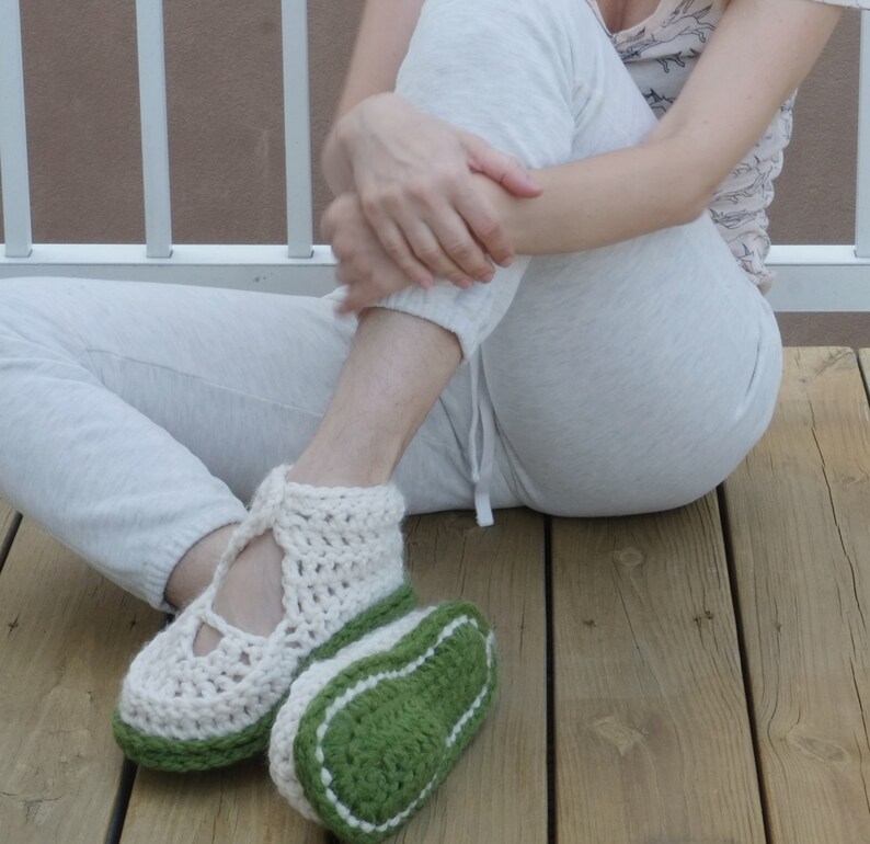 Op de afbeelding: Handgemaakte gehaakte pantoffels in cr&egrave;me en groen. De pantoffels hebben een gesloten ontwerp met een band over de bovenkant van de voet. De zolen zijn groen met een witte rand. De pantoffels zijn ontworpen voor binnenshuis.