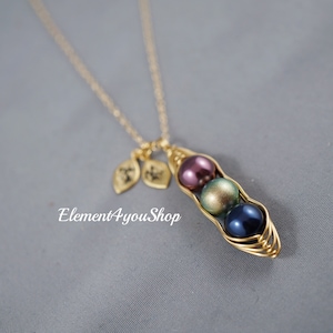 May include: A gold-colored necklace featuring a pea pod pendant with three colorful pearl beads: purple, green, and blue. Two leaf charms hang near the clasp. The text "Element4youShop" is visible.