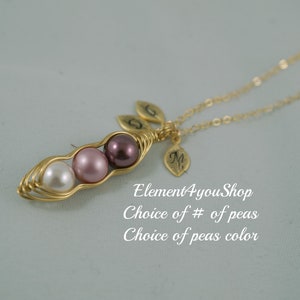 May include: A gold-colored necklace featuring a pea pod design with three pearl beads in white, pink, and purple. The necklace includes leaf charms and the text "Element4youShop".