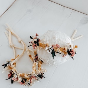 Puede incluir: Dos diademas florales y un gorro. Las diademas y el gorro est&aacute;n adornados con peque&ntilde;as flores rosas y blancas, hojas verdes y una cinta color mostaza. Los art&iacute;culos est&aacute;n sobre un fondo blanco.