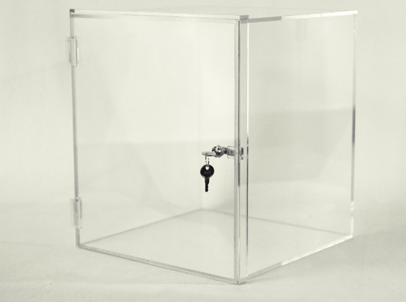K&ouml;nnte beinhalten: Ein transparentes Acryl-Vitrinen-Display mit Schloss und Schl&uuml;ssel. Die Vitrine ist w&uuml;rfelf&ouml;rmig und hat eine Fl&uuml;gelt&uuml;r.