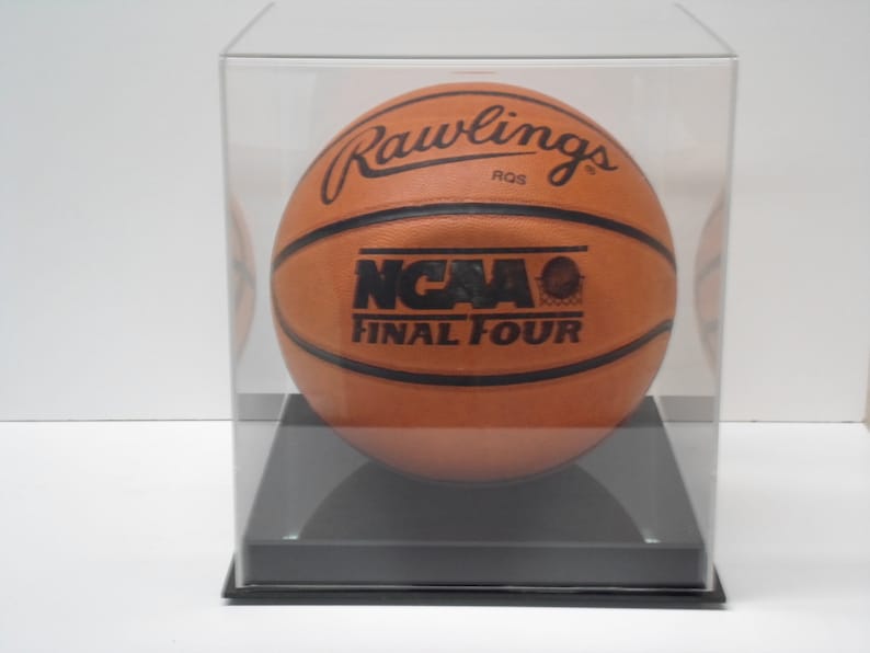 May include: A brown leather basketball with black stitching and the text "Rawlings", "NCAA", and "Final Four" in a clear acrylic display case.