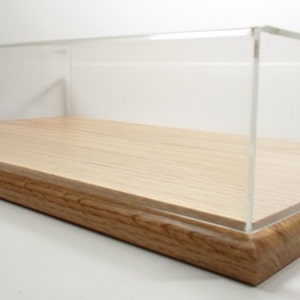 May include: A clear acrylic display case with a wooden base. The case has a rectangular shape and is made of clear acrylic. The base is made of wood and has a natural finish.
