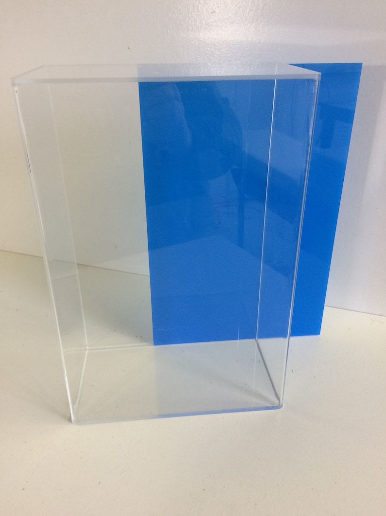 K&ouml;nnte beinhalten: Eine transparente Acryl-Vitrine mit einer blauen Acryl-R&uuml;ckwand. Die Vitrine ist leer und hat eine rechteckige Form.