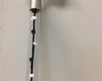 May include: A clear acrylic cane with a silver metal handle and a black string with white and green accents running through the shaft.