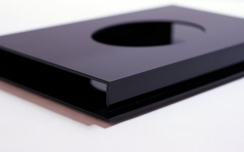 May include: A glossy black rectangular object with a circular cutout. The object has a sleek, modern design and appears to be made of a solid, reflective material. The edges are sharp and well-defined, creating a minimalist aesthetic.