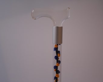 May include: A clear glass cane handle with a silver metal band and a decorative floral design featuring blue and orange flowers.