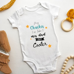 May include: White baby onesie with the text "My Chachu is like my dad but Cooler" in black with yellow stars and a blue banner.