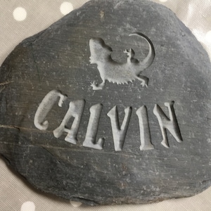 Piedra de memoria tallada a mano que incluye el nombre de su ser querido, con la silueta de un lagarto/gecko encima