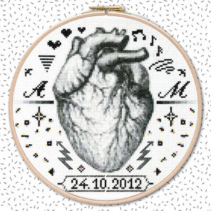 May include: A black and white cross-stitch embroidery of a human heart with musical notes and the letters A and M. The date 24.10.2012 is stitched below the heart.