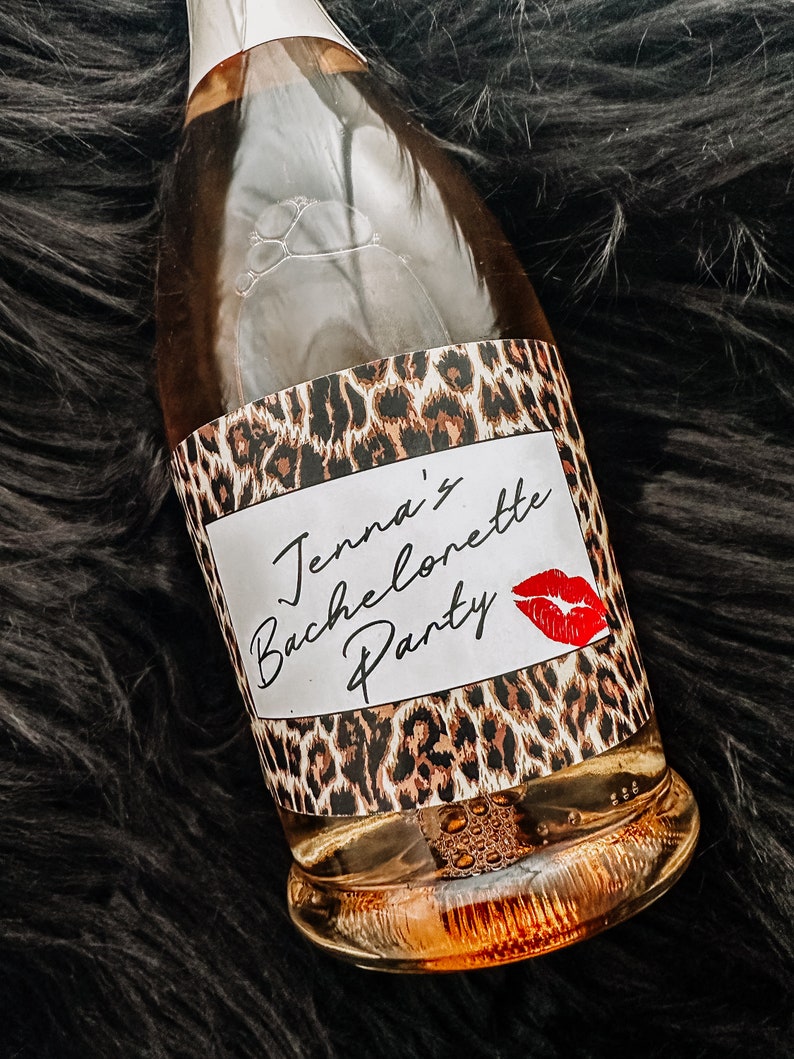 Puede incluir: Una botella de vidrio transparente con una etiqueta de estampado de leopardo que dice "Jenna's Bachelorette Party" con una marca de beso de l&aacute;piz labial rojo.