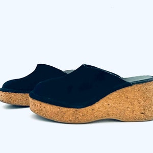 May include: Pair of black suede platform clogs with cork wedge heels.