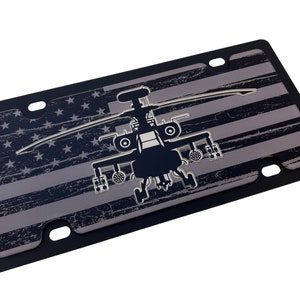 May include: A black and silver license plate with a distressed American flag design and a silver silhouette of a helicopter.