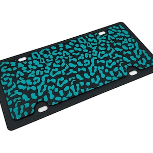 May include: Black license plate frame with a teal leopard print design.