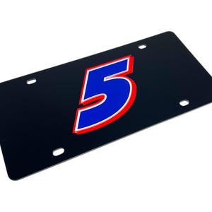 May include: Black license plate with the number 5 in blue, outlined in red and white. The license plate has four mounting holes and a glossy finish. The number is large and centered on the plate.