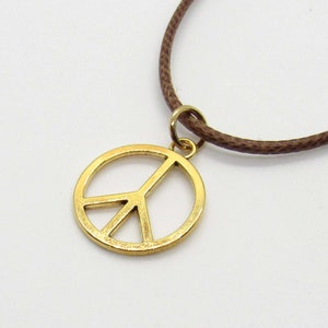 May include: A gold peace sign pendant necklace with a brown cord.