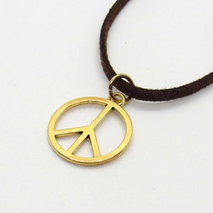 May include: A gold peace sign pendant necklace with a brown suede cord.
