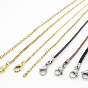 May include: Five different types of chain and cord necklaces with silver lobster clasps. The chains are gold and include a curb chain, a box chain, and a ball chain. The cords are black and brown.