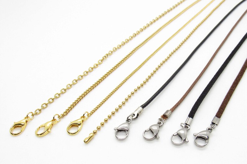 May include: Five different types of chain and cord necklaces with silver lobster clasps. The chains are gold and include a curb chain, a box chain, and a ball chain. The cords are black and brown.