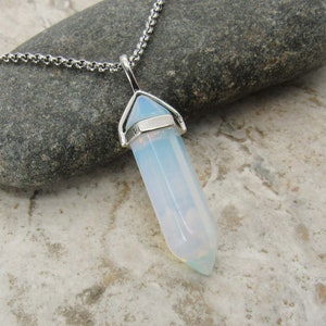 May include: A silver chain necklace with a white opal point pendant. The pendant is a clear, faceted crystal with a silver bail.