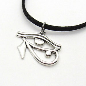 Puede incluir: Un collar de cord&oacute;n de ante negro con un colgante de plata en forma de Ojo de Horus.
