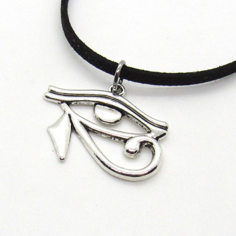 Puede incluir: Un collar de cord&oacute;n de ante negro con un colgante de plata en forma de Ojo de Horus.