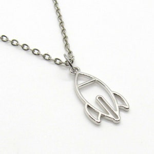 May include: A silver chain necklace with a silver rocket ship pendant. The rocket ship is a simple outline design.