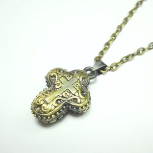May include: A gold and silver cross pendant necklace with an intricate design. The cross is detailed with floral patterns and a smaller cross in the centre.
