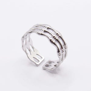 May include: A silver skeleton hand ring with a detailed design. The ring is adjustable and can be worn on any finger.