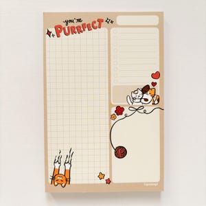 May include: A tan notepad with a grid pattern and the words "you're Purrfect" in red. The notepad features cartoon cat illustrations, hearts, flowers, and a ball of yarn. It includes a to-do list section and a blank space for notes.