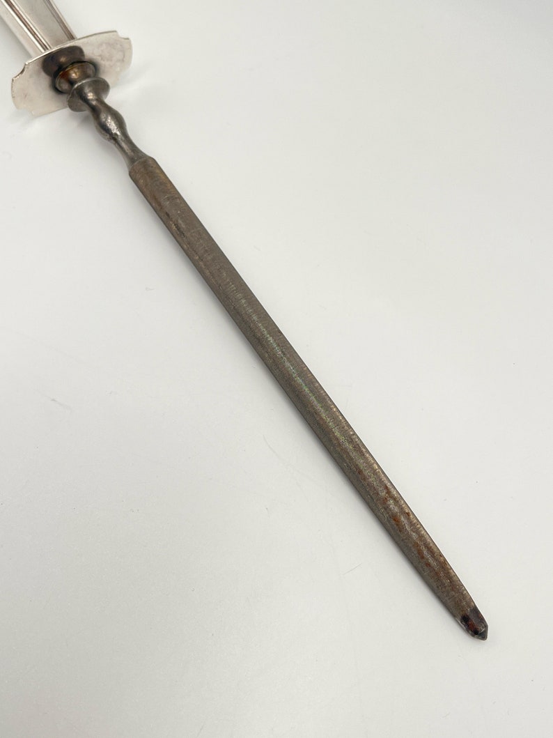 May include: A silver-plated knife sharpener with a steel blade. The blade is slightly rusted.
