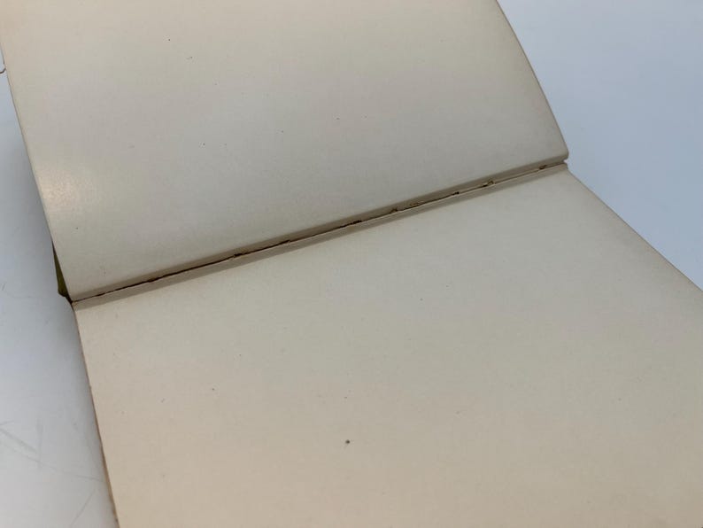 Puede incluir: Un cuaderno blanco cerrado, en blanco, con encuadernaci&oacute;n cosida.