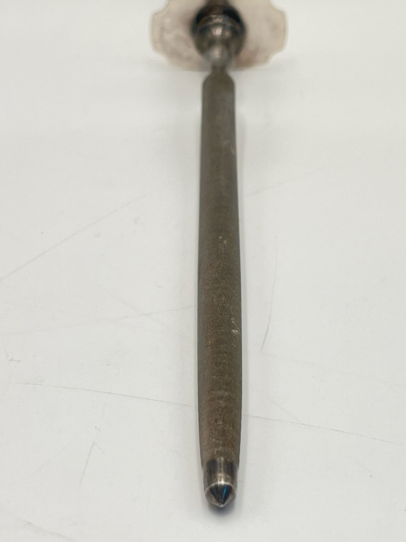 May include: A silver metal knife sharpener with a diamond-shaped tip and a textured surface.