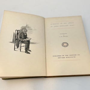 Puede incluir: Un libro abierto con una ilustraci&oacute;n en blanco y negro de un hombre sentado en una silla y leyendo. La p&aacute;gina del t&iacute;tulo del libro dice "The Mystery of the Seaport by James Whitcomb Riley". El libro fue publicado por The Century Co. en Nueva York en 1907.