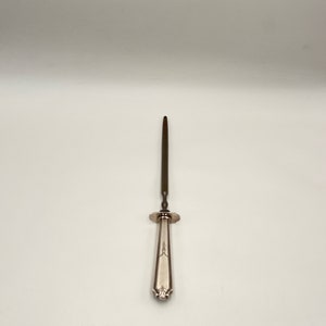 May include: A silver-plated skewer with a long, thin, pointed blade and a decorative handle.