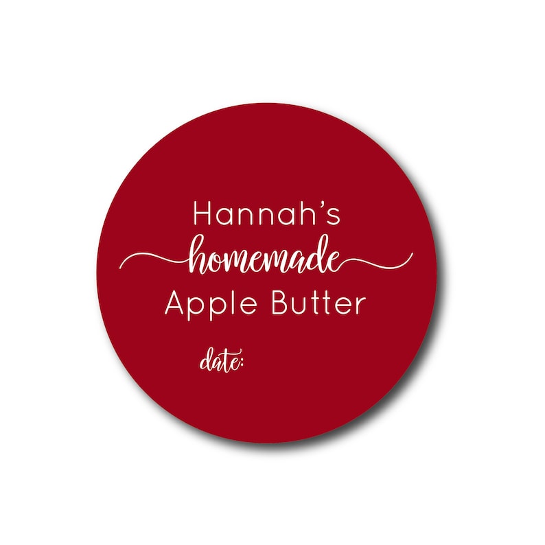 May include: A round, deep red label with the text "Hannah's homemade Apple Butter" in white script. The word "homemade" is in cursive. Below the text is the word "date:" in a smaller font.