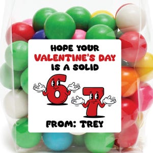 Pode incluir: Um saco transparente de celofane cheio de bolas de goma coloridas. Uma etiqueta branca na bolsa diz "HOPE YOUR VALENTINE'S DAY IS A SOLID 67 FROM: TREY" em texto vermelho e preto. As bolas de goma s&atilde;o de v&aacute;rias cores.