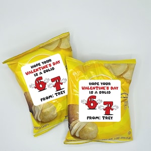 Pode incluir: Duas embalagens amarelas de batatas fritas com r&oacute;tulos brancos. Os r&oacute;tulos dizem "HOPE YOUR VALENTINE'S DAY IS A SOLID" com os n&uacute;meros de desenhos animados 6 e 7. O texto "FROM: TREY" tamb&eacute;m est&aacute; nos r&oacute;tulos. As embalagens cont&ecirc;m batatas fritas.