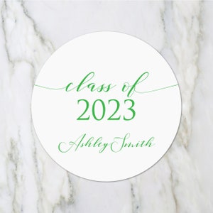 May include: White circle sticker with green text that reads "class of 2023" and "Ashley Smith".