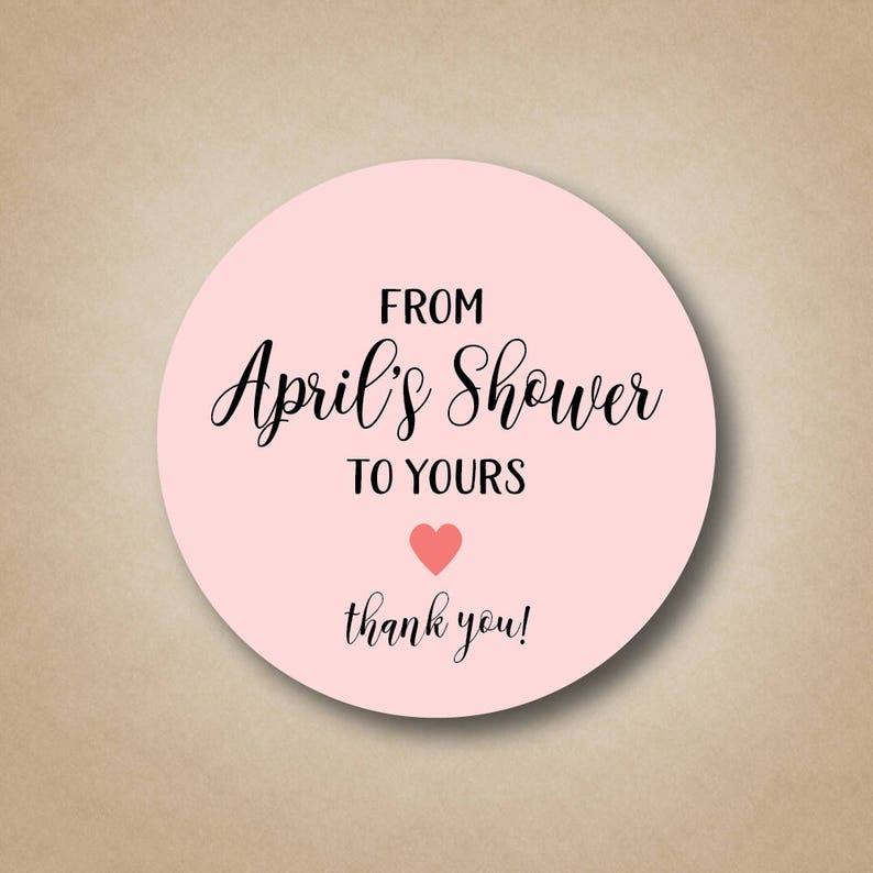 May include: Pink round sticker with the text "From April's Shower to Yours" in black cursive font. A small pink heart is below the text and the words "thank you!" are below the heart.