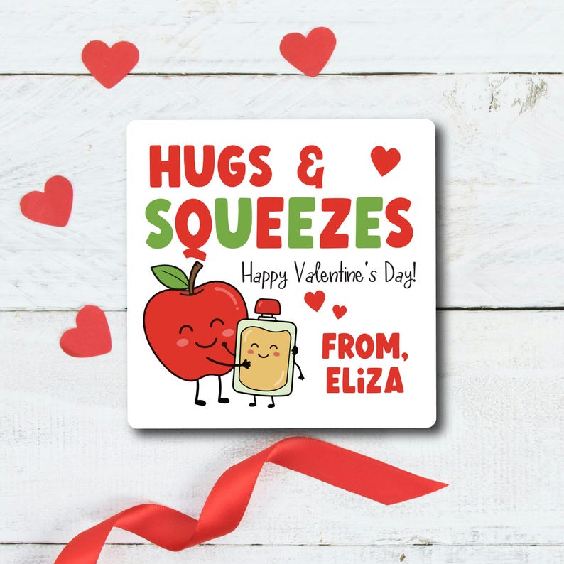 K&ouml;nnte beinhalten: Eine quadratische Valentinstagskarte mit einem Cartoon-Apfel, der eine Saftbox umarmt. Der Text lautet "Hugs & Squeezes, Happy Valentine's Day!" und "From, Eliza". Rote Herzen und ein rotes Band schm&uuml;cken die Karte.