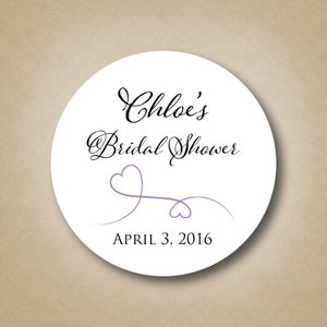 May include: White round sticker with black text that reads "Chloe's Bridal Shower" and "April 3, 2016". A purple heart design with a swirl is below the text.