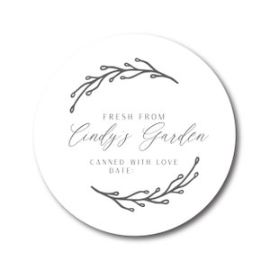 May include: A round white label with gray text and botanical illustrations. The text reads "FRESH FROM Cindy's Garden CANNED WITH LOVE DATE:" with a decorative floral design. The label is suitable for homemade goods.